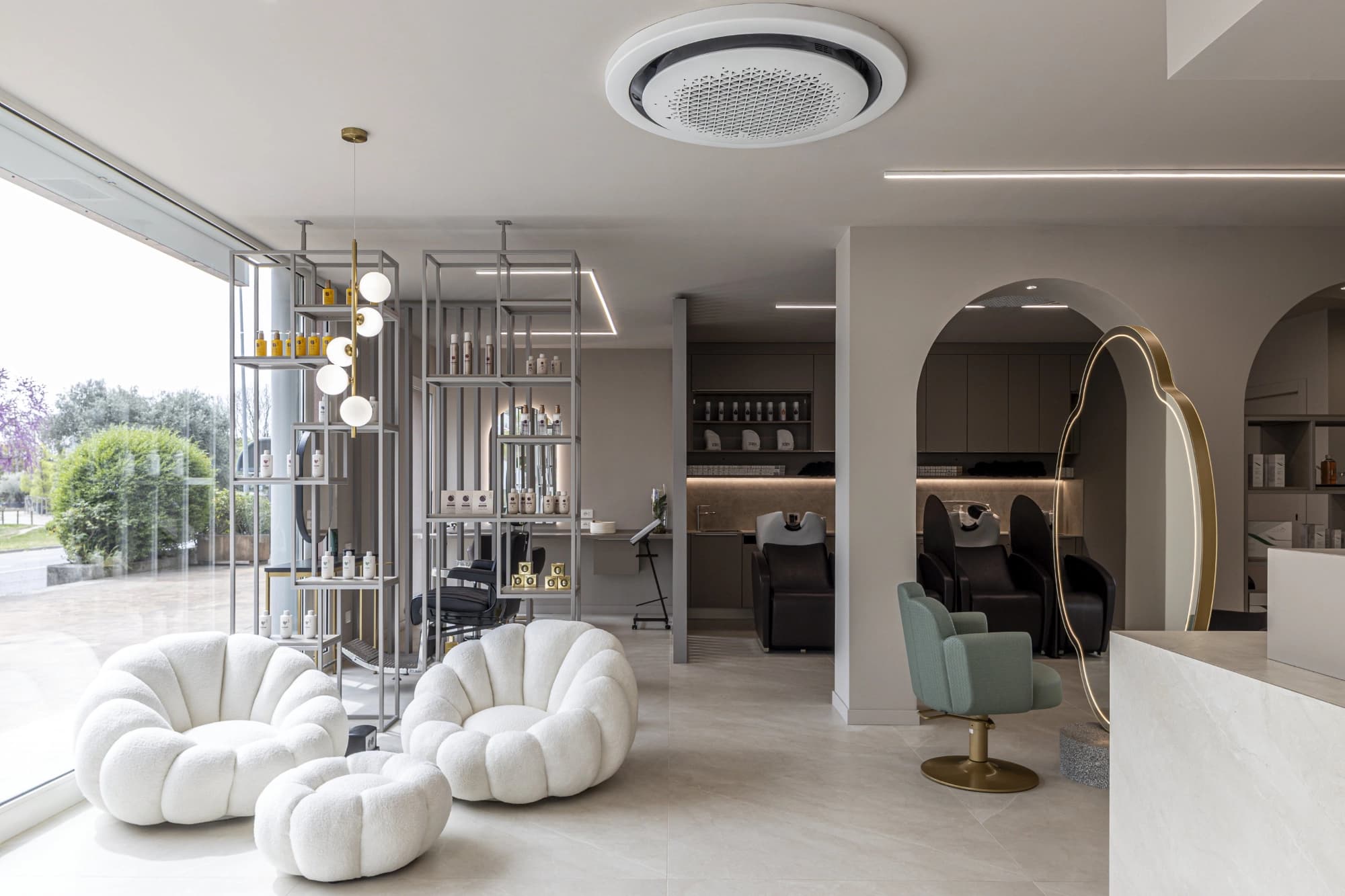 Waiting area with white boucle armchairs and large windows in the salon