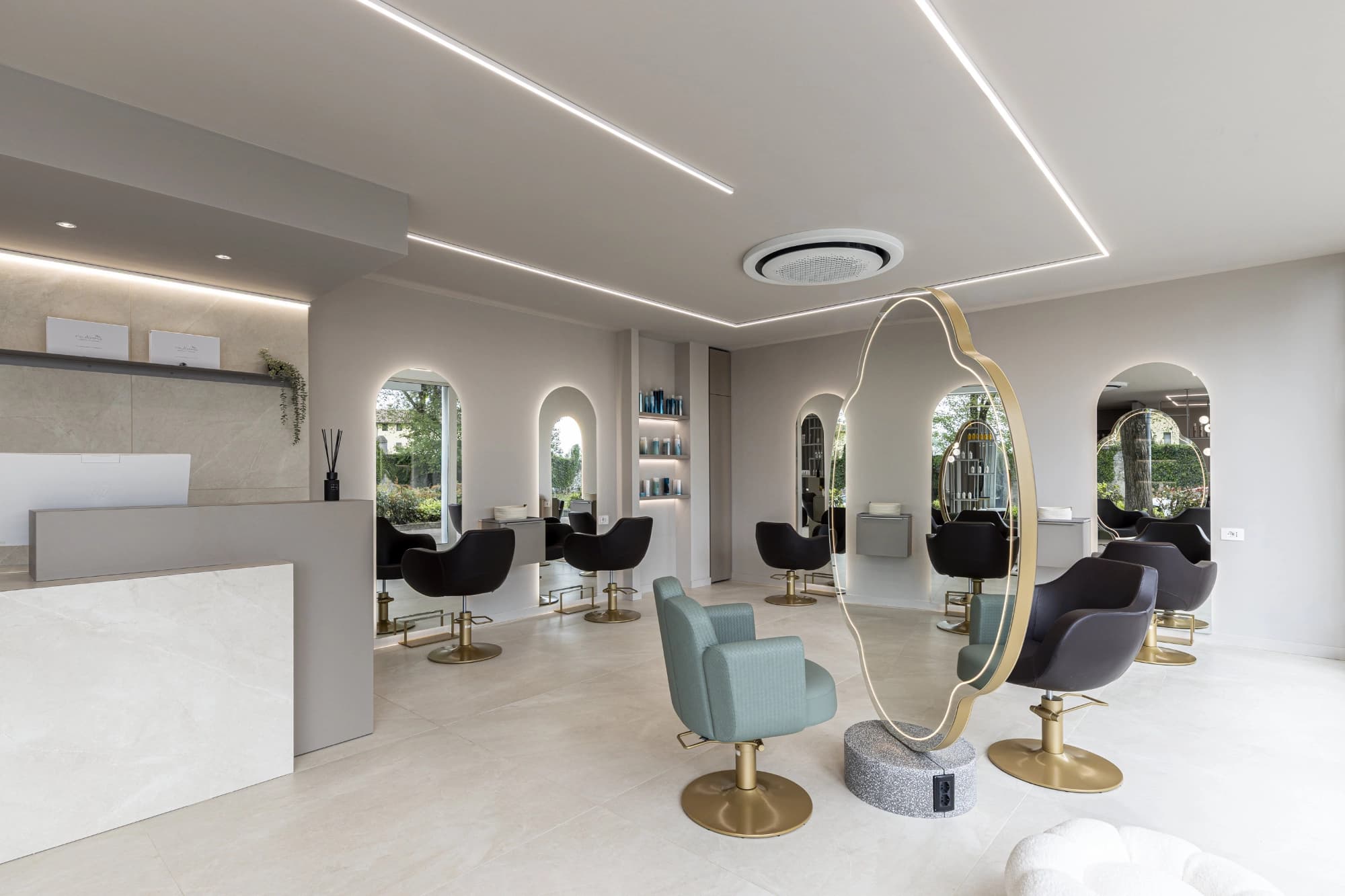Styling stations with arched backlit mirrors and gold-based chairs in the Tagliati X il Successo salon